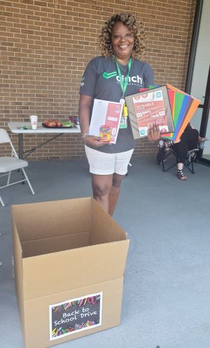 A Cinch employee, holding folders, crayons and other school supplies, volunteers at the Back to School Drive