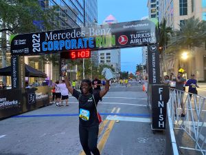 A Cinch employee cheers as she crosses the finish line at the 2022 Mercedes-Benz Corporate Run