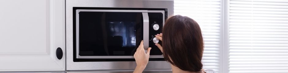 A woman setting her microwave