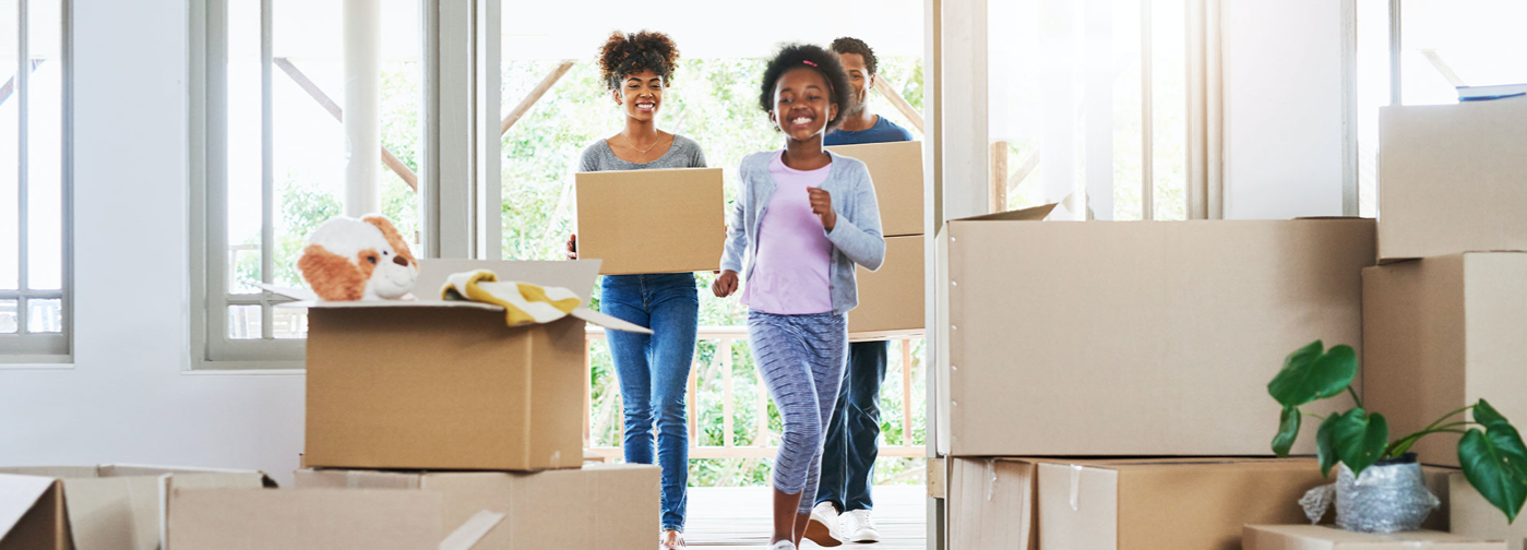 Young family walking into home with unpacked boxes