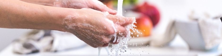 A woman washing her hands over a sink with a garbage disposal