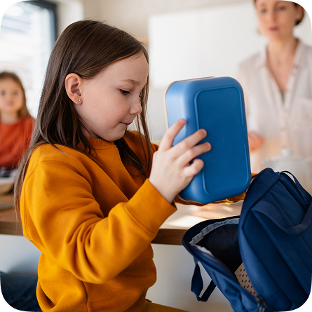 Child packing a lunchbox into a backpack at home, a back-to-school moment made easier with reliable home warranty plans protecting household appliances