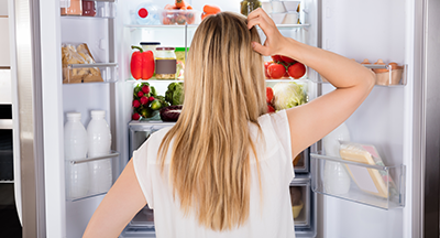 woman thinking how she will fix the freon leak - standing in front of fridge