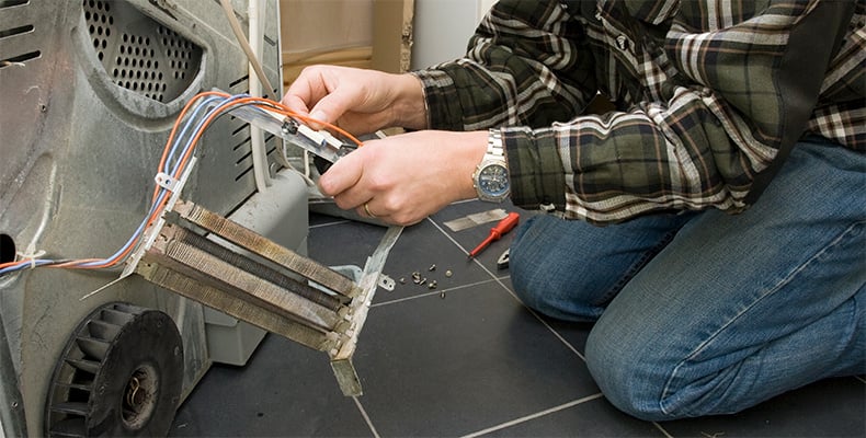 a service technician fixing a broken heating element on dryer