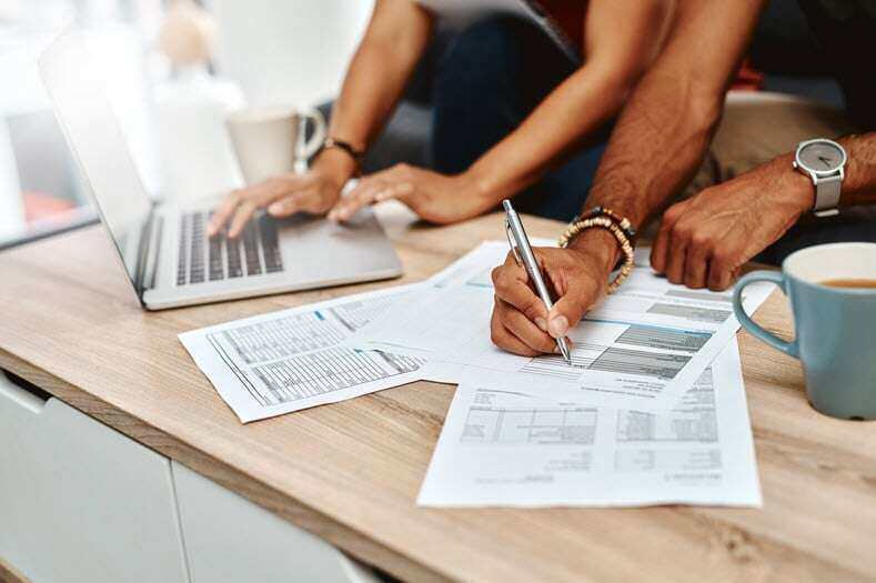 People signing important documents on a desk, possibly finalizing a home purchase with the added assurance of a home warranty.