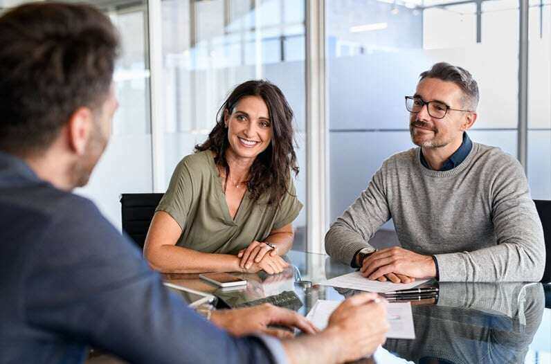 Couple in a consultation with a financial advisor, discussing investment strategies including the benefits of a home warranty.