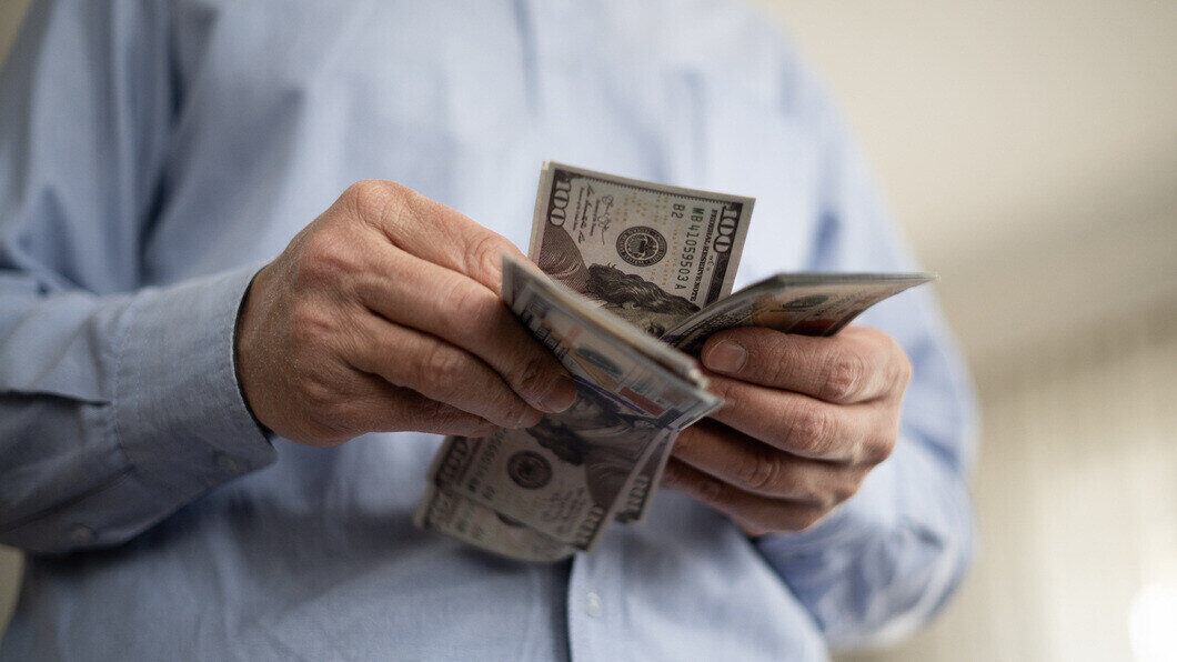 Man counting dollars at home wondering if he can afford a home warranty plan